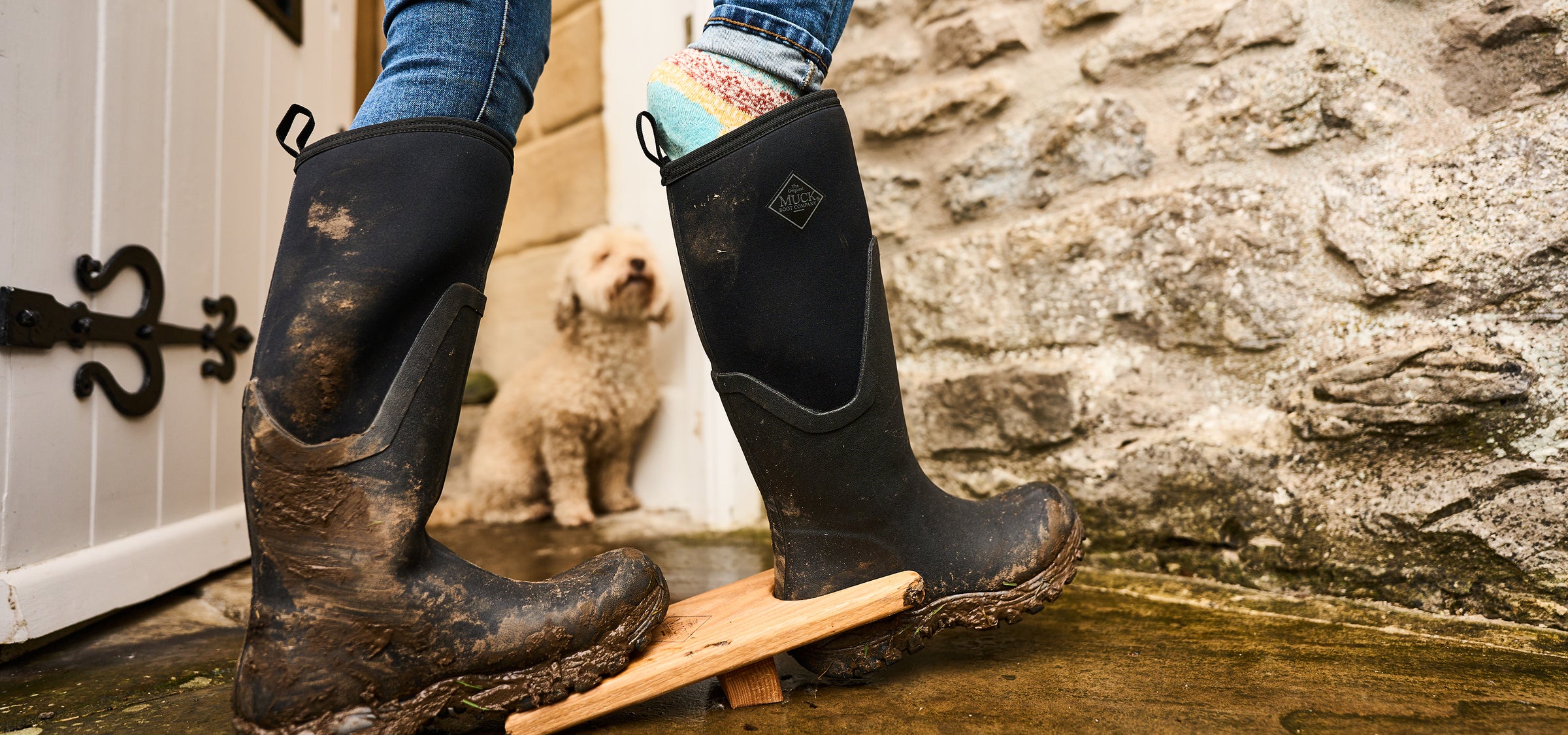 Person, die einen Gummistiefel mit einem Stiefelknecht auszieht